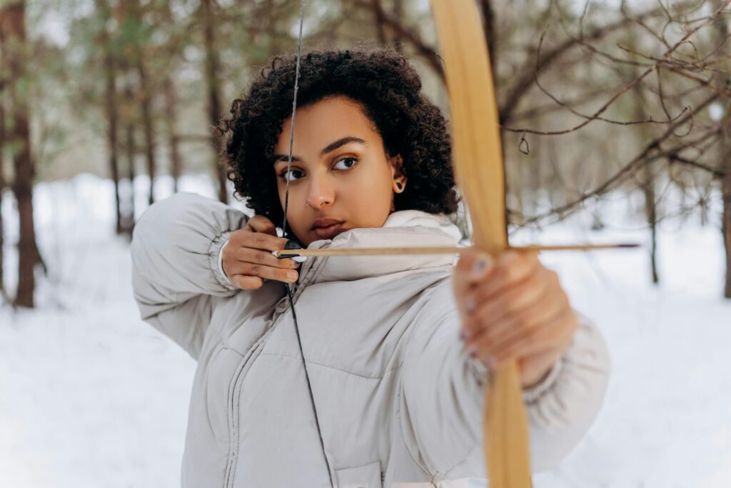 A Woman Holding a Bow and Arrow at the Forest